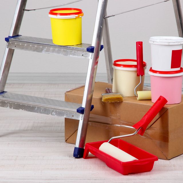 Photo: Paint cans, a paint roller and a stepladder on a cardboard box