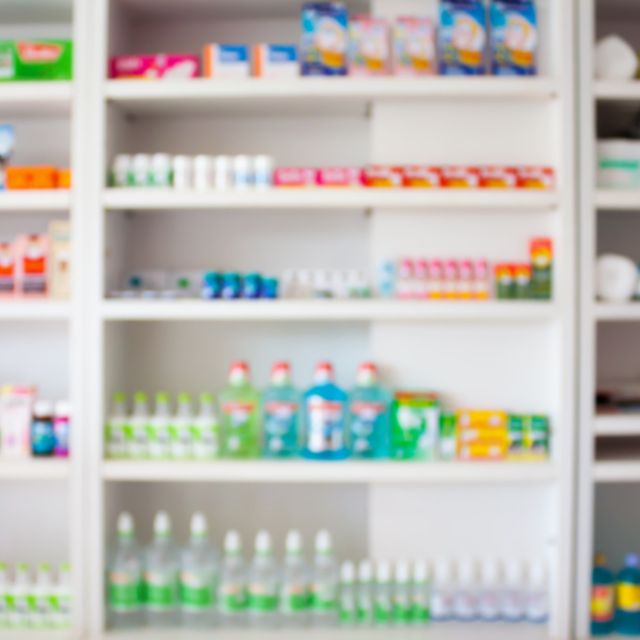 Photo: White shelves stocked with medicine boxes and bottles in a pharmacy