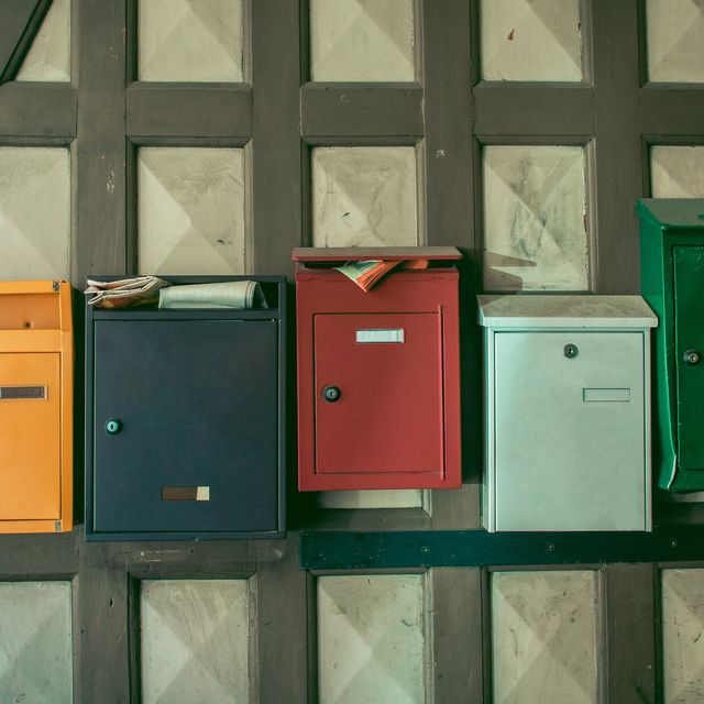 Photo: Five colorful mailboxes in yellow, black, red, mint and green mounted on a wooden wall