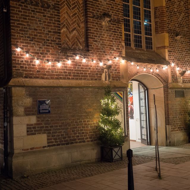 Photo: Red brick building with string lights and an arched doorway at dusk