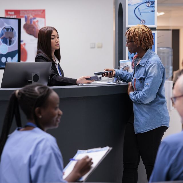 Photo: Customers and staff talking at a service counter in a busy office