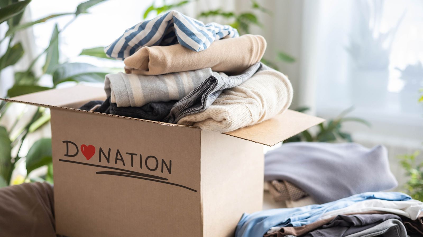 Cardboard donation box filled with folded clothes and sweaters