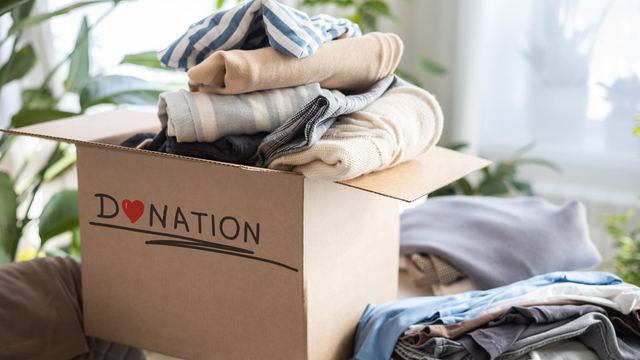 Cardboard donation box filled with folded clothes and sweaters